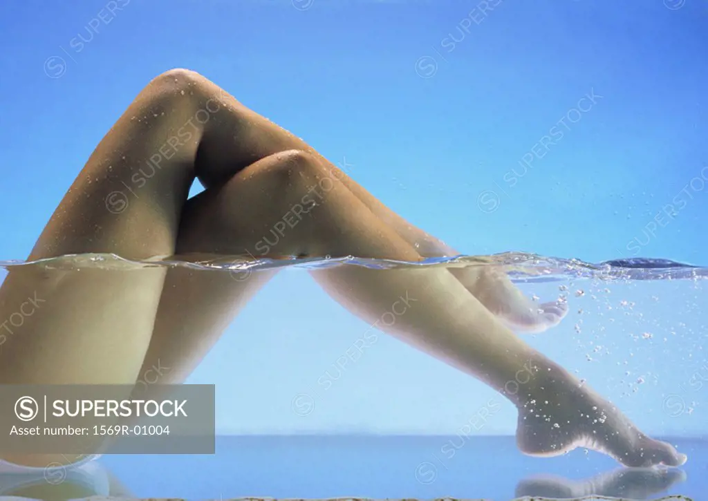 Woman´s bare legs crossed in water