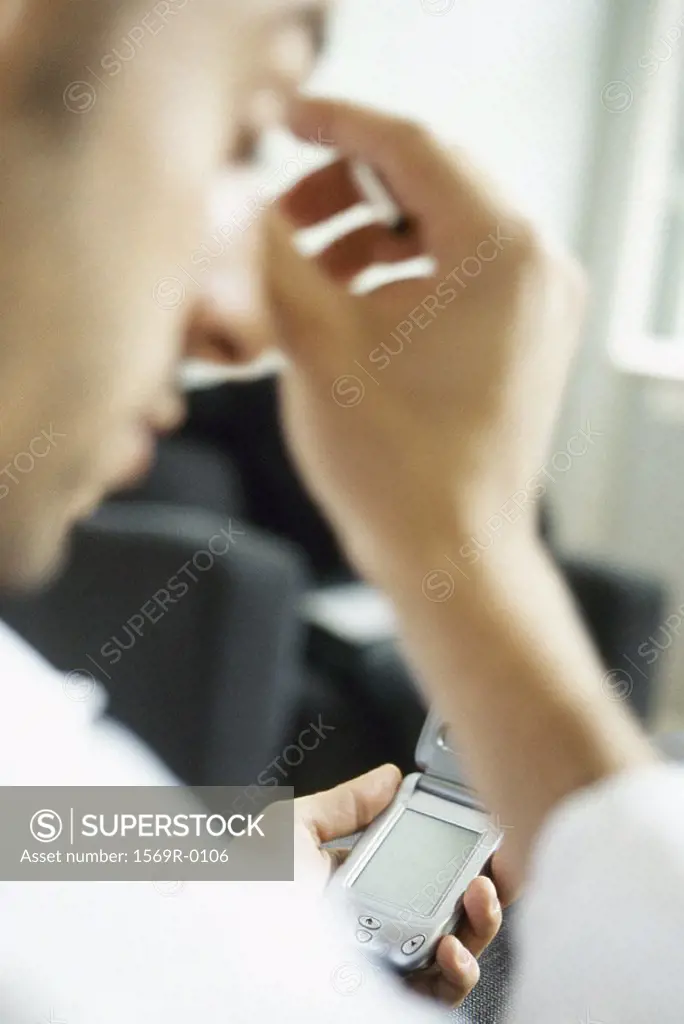 Man using cell phone, rubbing head
