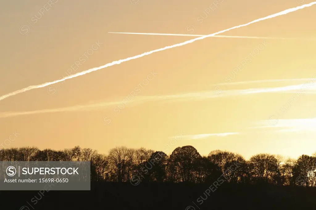 Vapor trails in sky at sunset