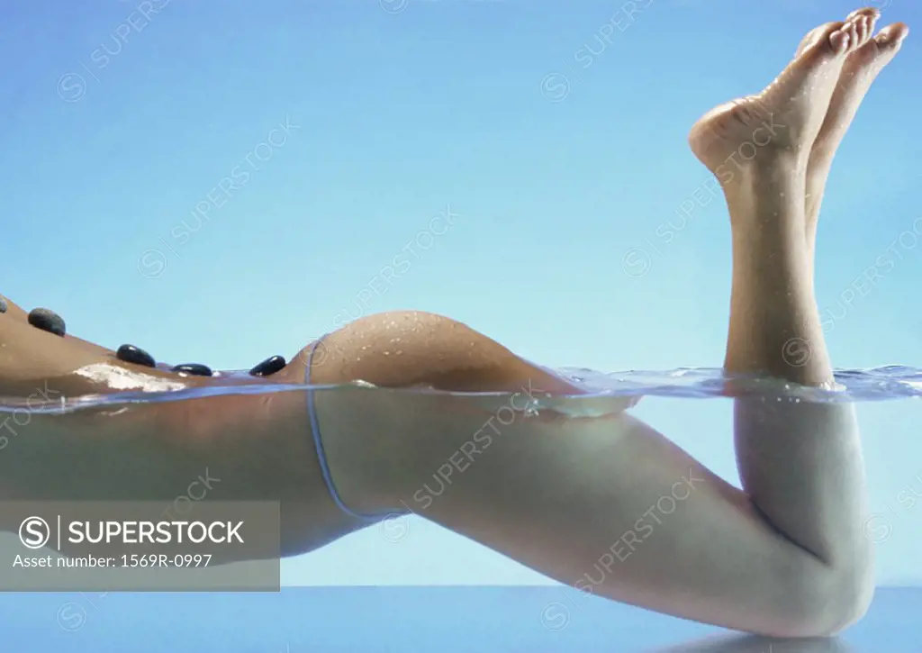 Woman in water doing lastone therapy, chest down, side view