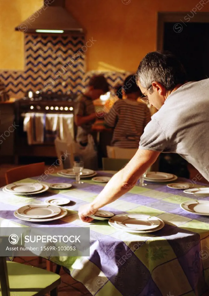 Man setting table, children standing in background