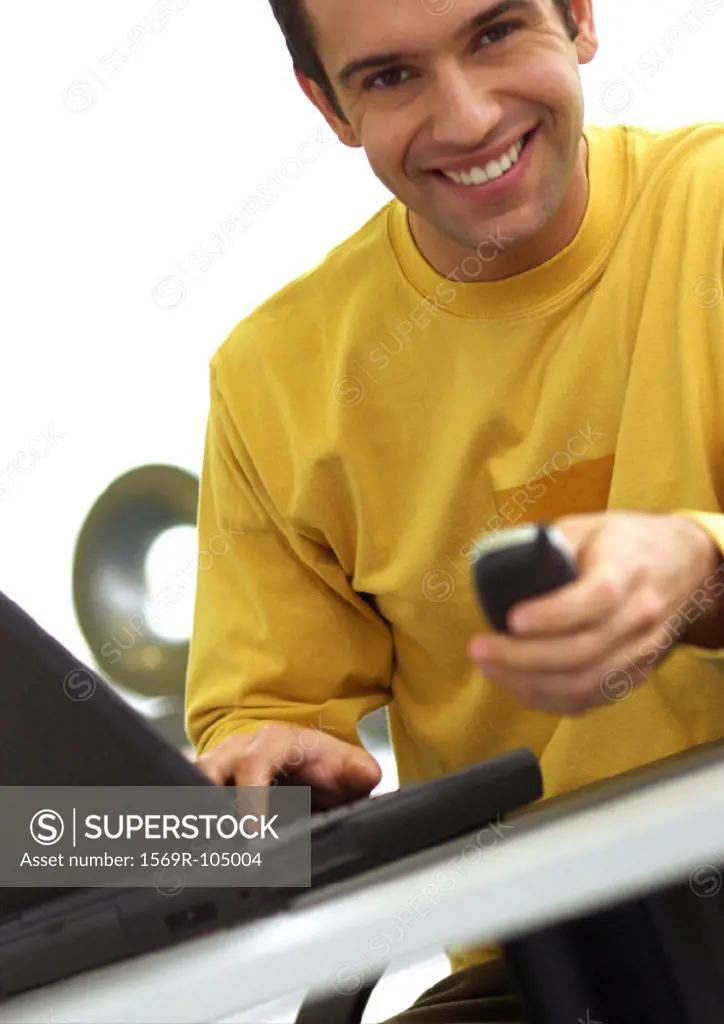 Man with laptop computer and cell phone, smiling