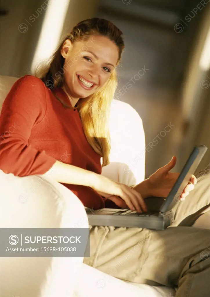 Woman holding laptop computer on knees, portrait