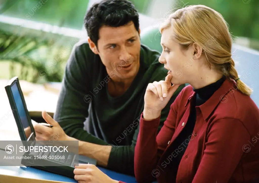 Man and woman talking and using laptop computer