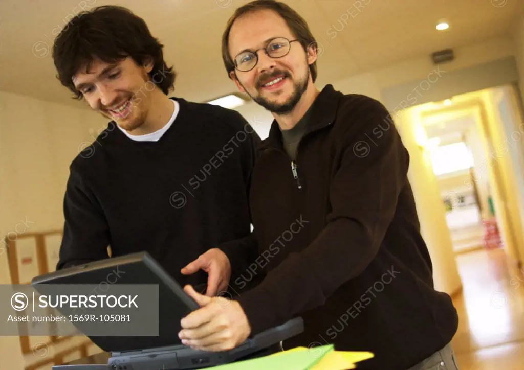 Two men with laptop computer, smiling