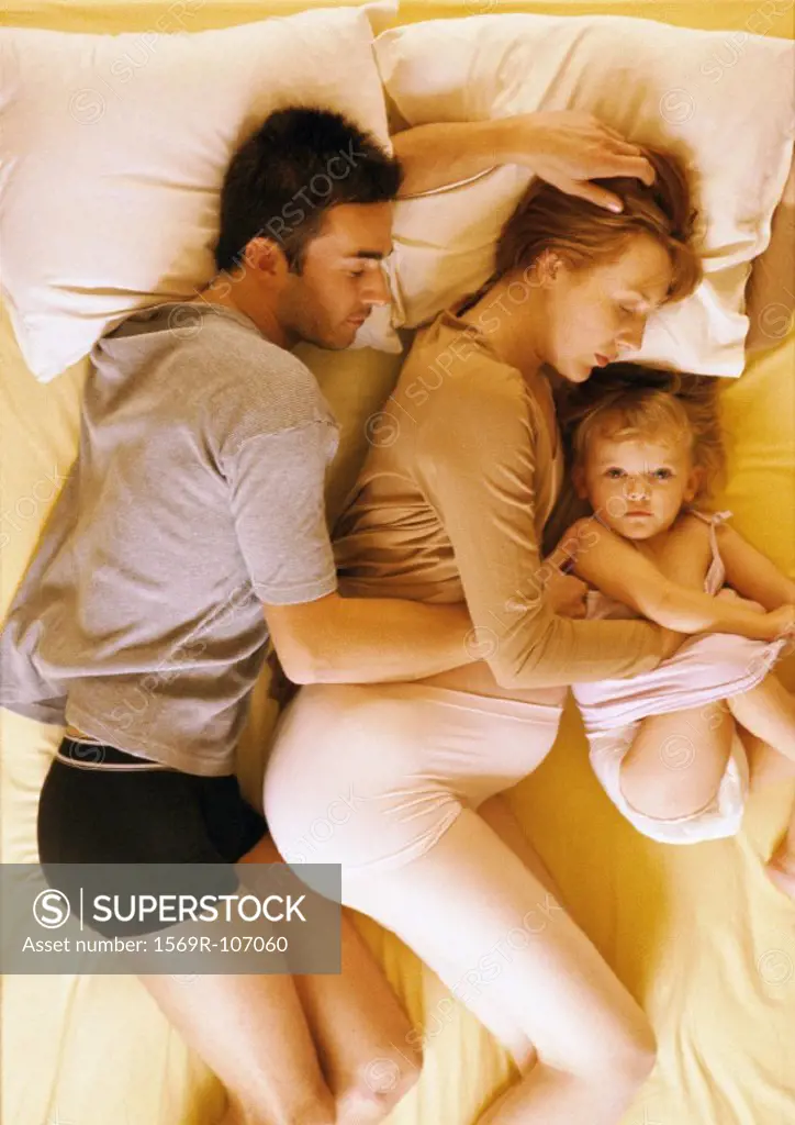 Man, pregnant woman and child lying in bed, elevated view
