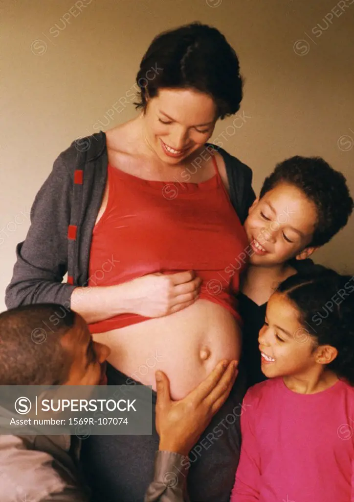 Man and children looking at pregnant woman´s exposed stomach