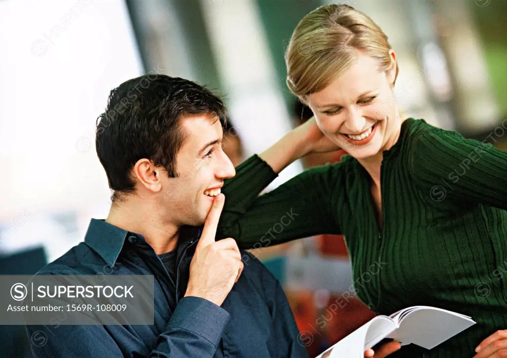 Businessman and woman looking at book, smiling