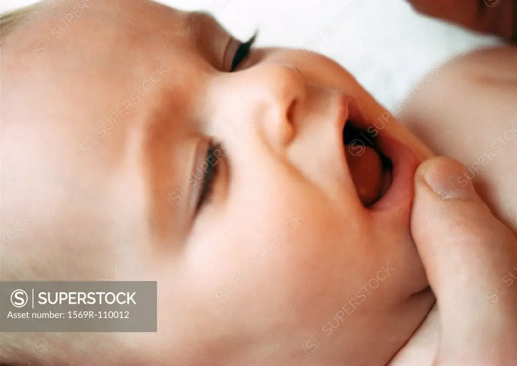 Baby´s face with adult finger on chin, close-up