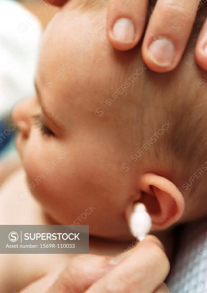 Baby having ear cleaned with cotton swab, close-up