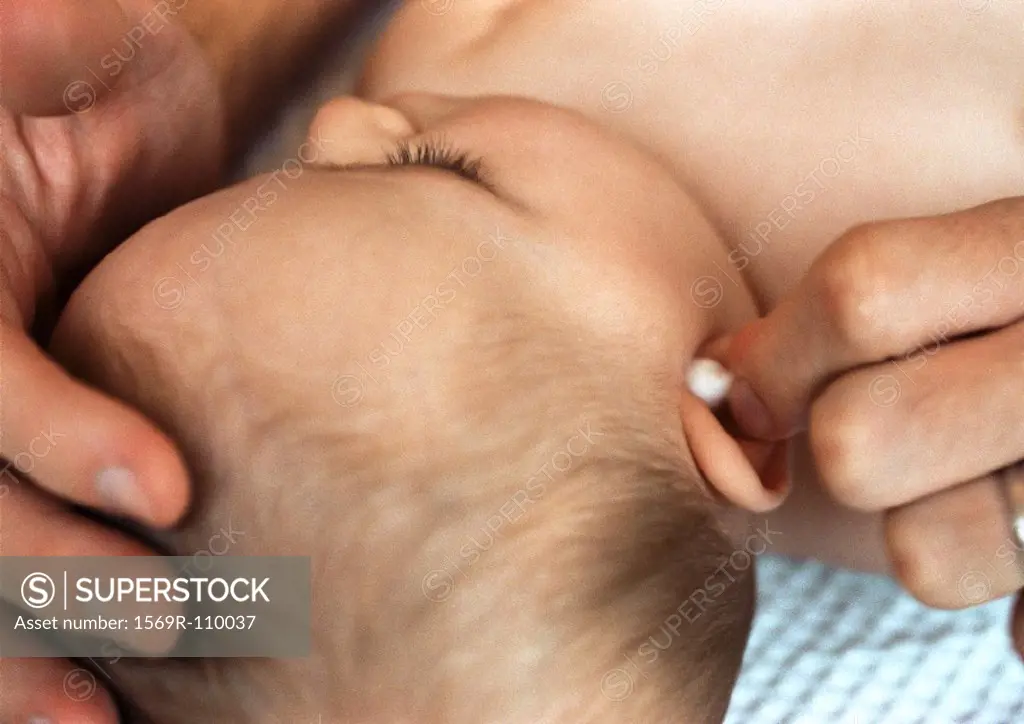 Baby having ear cleaned with cotton swab, close-up