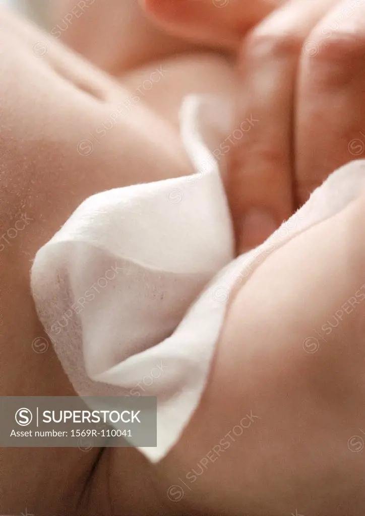 Adult hand wiping baby, close-up