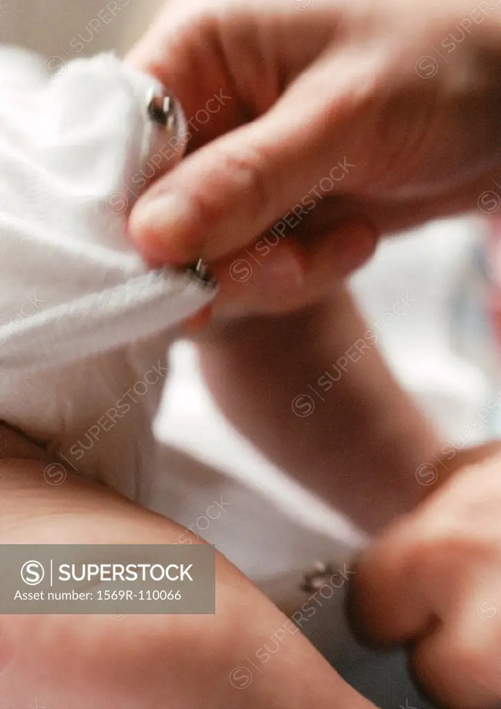 Adult closing baby´s clothing between legs, close-up