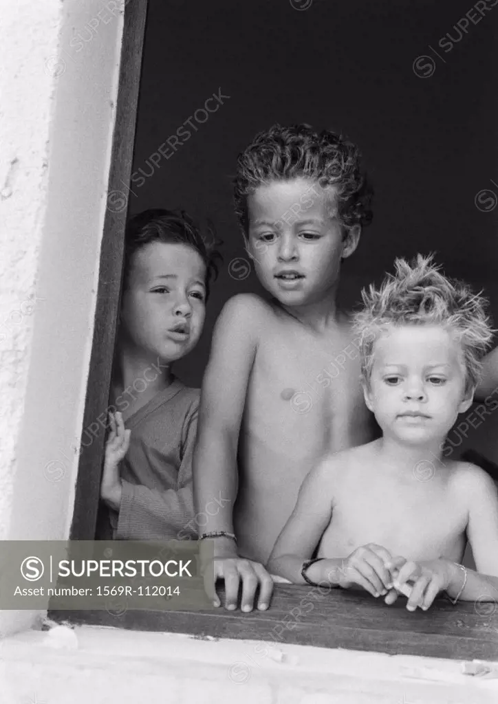 Children standing at windowsill, b&w