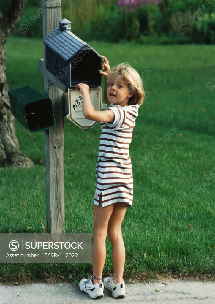 Girl with hand in mailbox, looking into camera