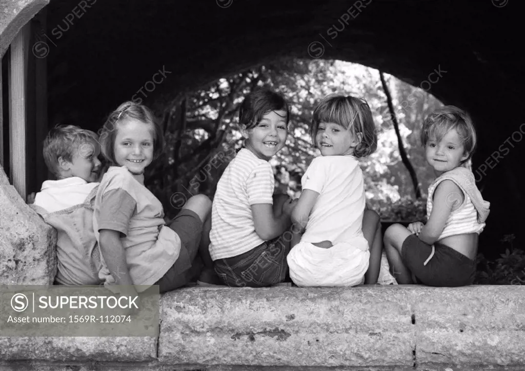 Five children sitting under an arch, b&w