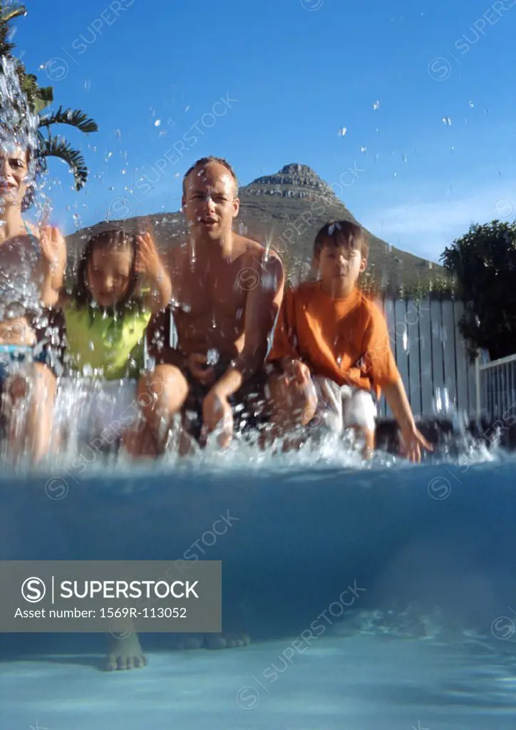 Family splashing at edge of pool, shot partially underwater