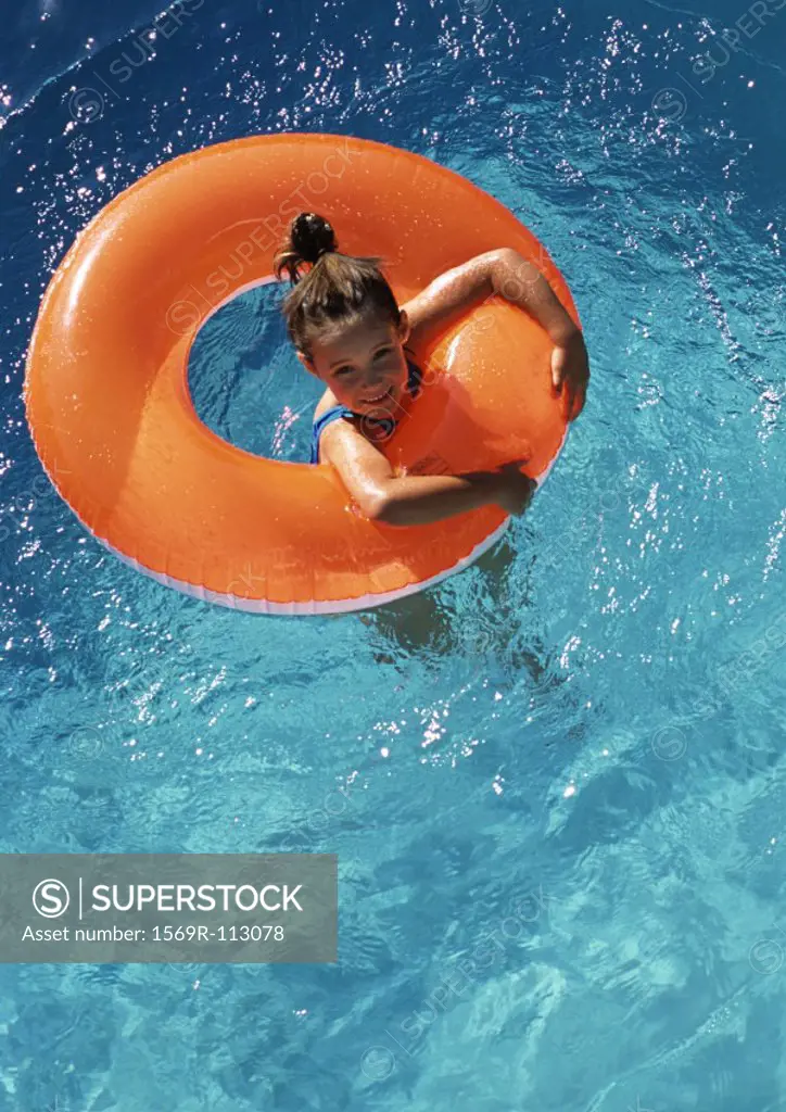 Young girl floating in inner tube in pool, shot from above