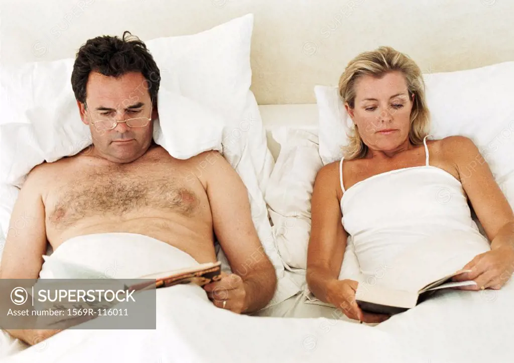 Couple lying in bed, reading