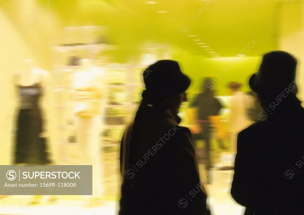 Silhouettes in front of clothing shop window, blurred