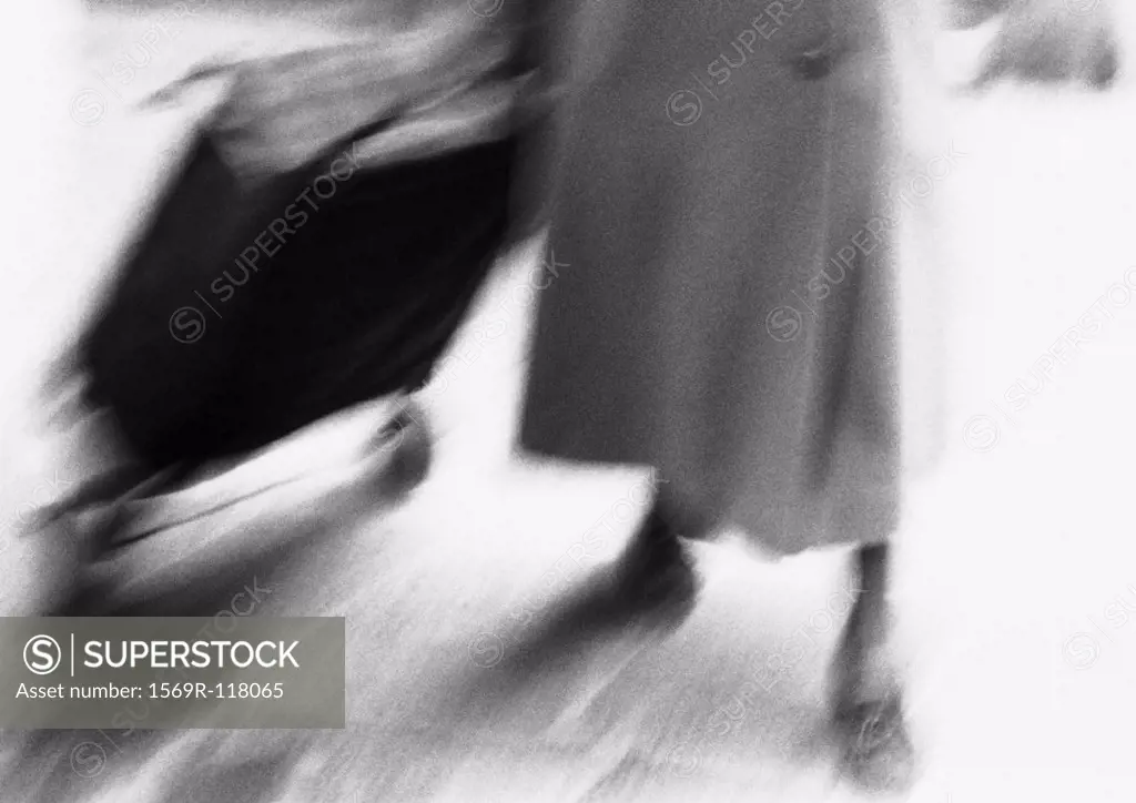Woman pulling shopping cart, low section, blurred, b&w