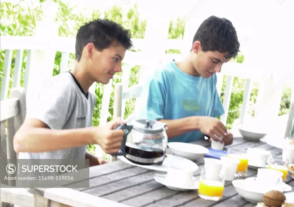 Two teenage boys having breakfast outside
