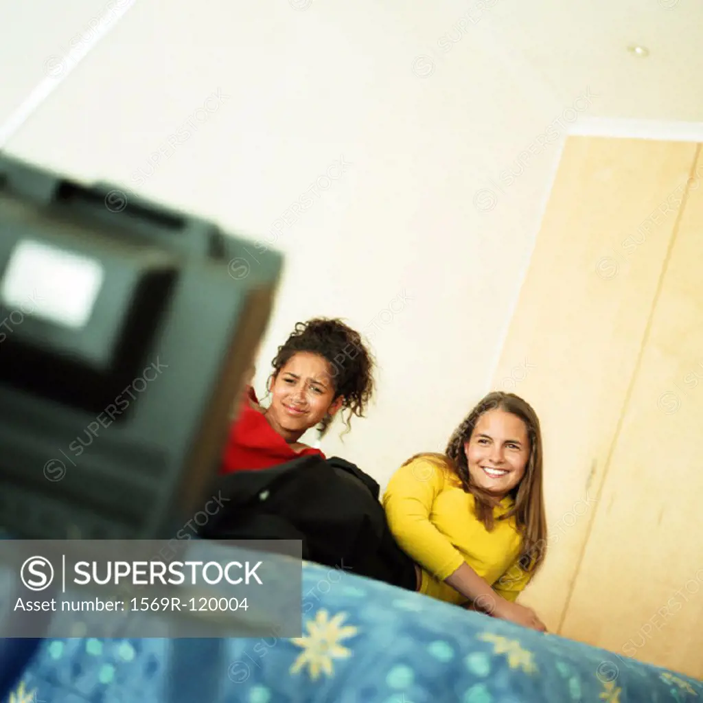 Two girls on bed watching television
