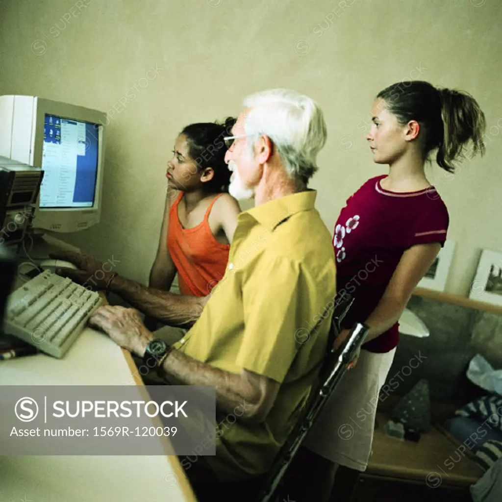 Mature man and two girls using computer