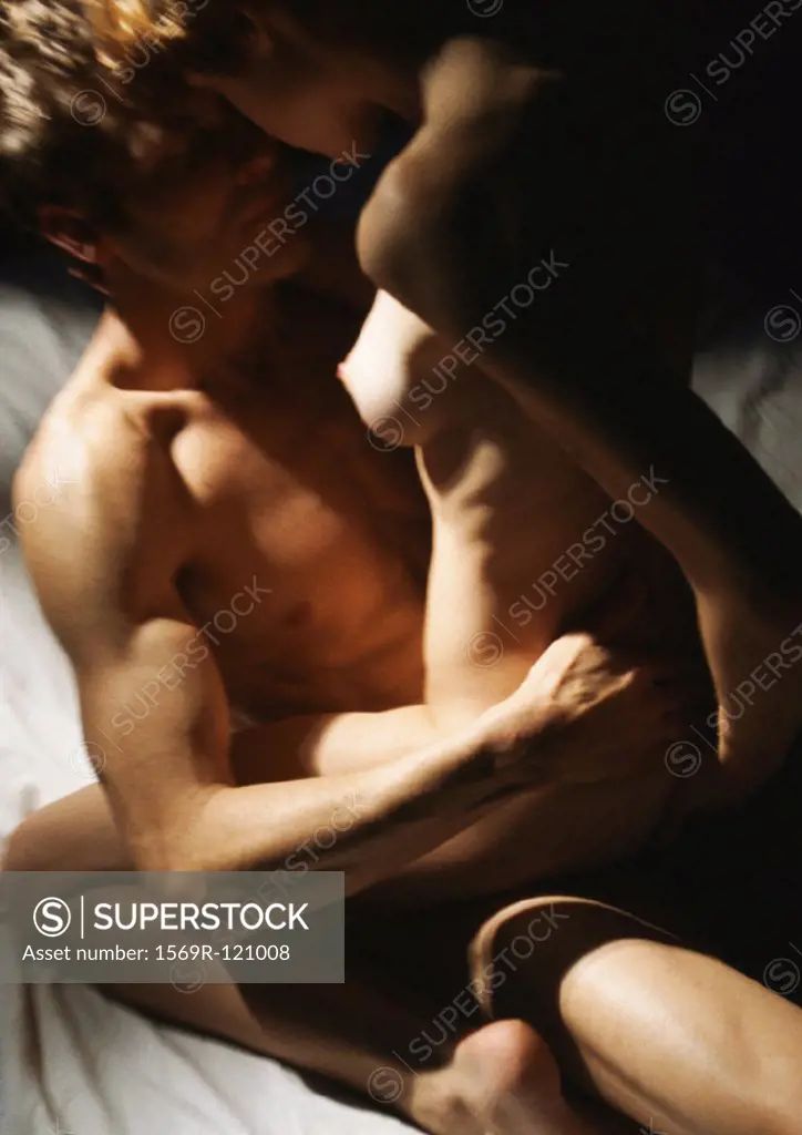 Nude couple making love, woman straddling man, close-up