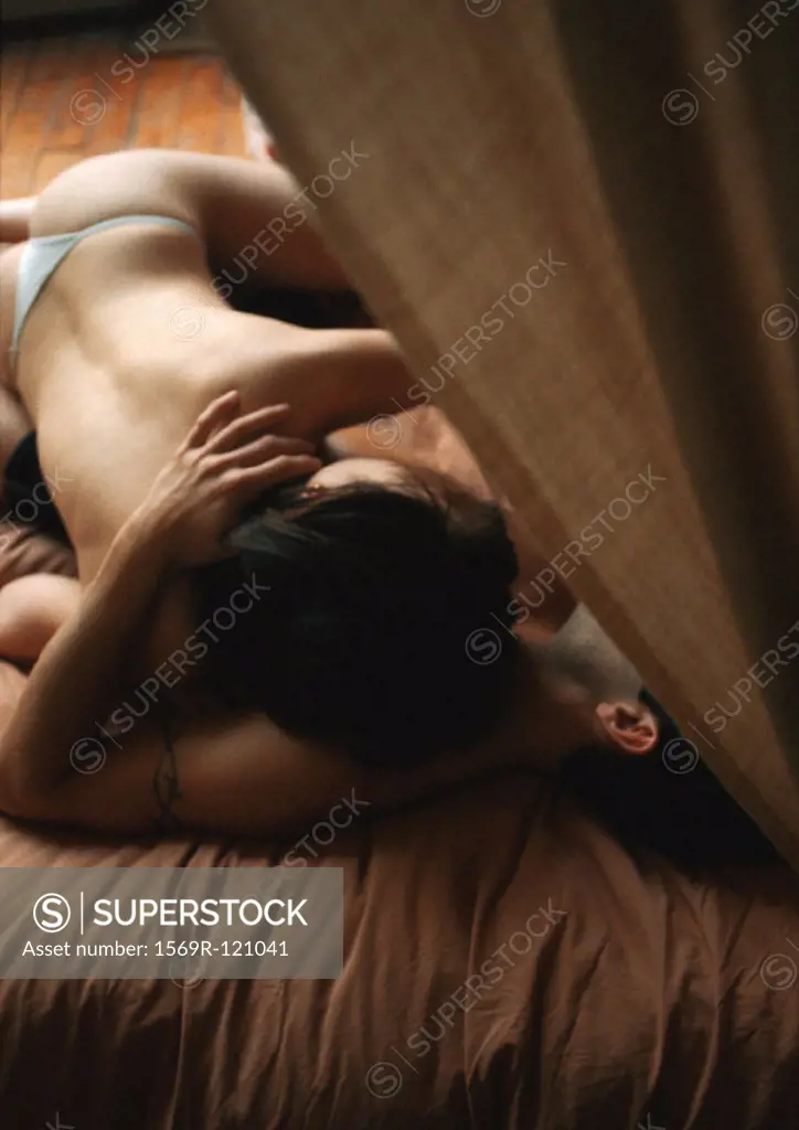 Semi-nude couple embracing on bed