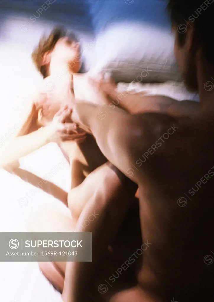 Nude couple, man caressing woman lying on bed, blurred