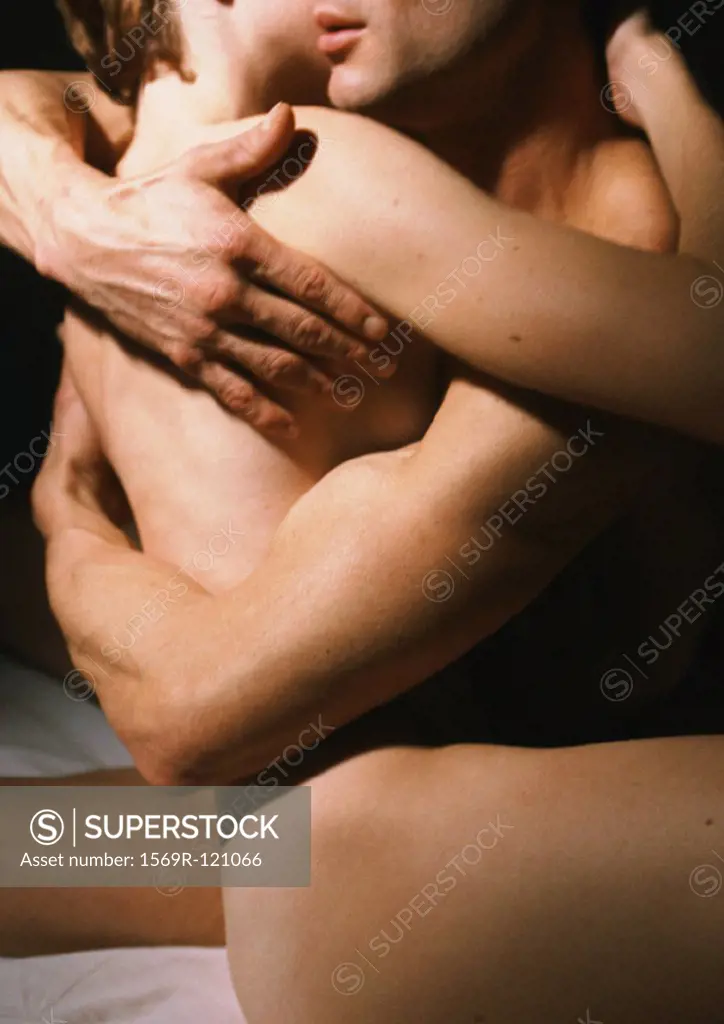 Nude couple embracing, mid-section, side view