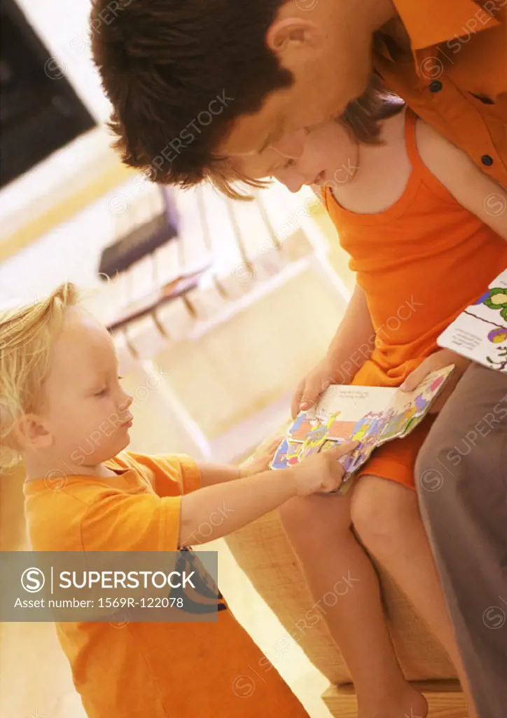 Father and children reading book, close-up