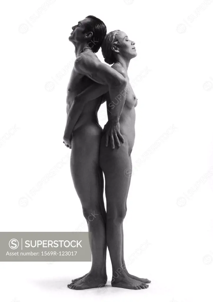 Nude man and woman standing back to back, hands on each other, side view, b&w