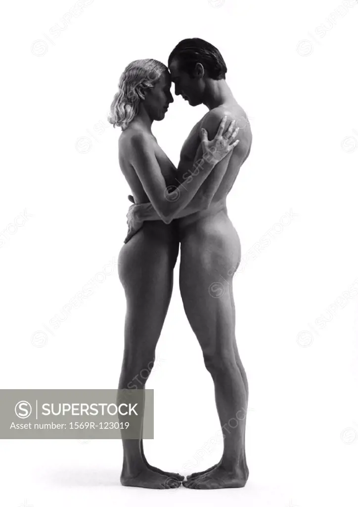 Nude man and woman standing face to face, embracing, side view, b&w