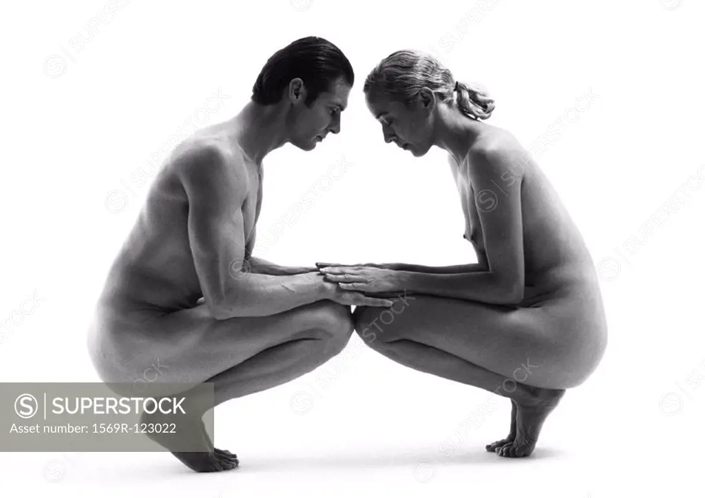 Nude man and woman crouching face to face, b&w