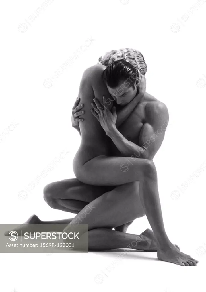Nude man kneeling holding nude woman on lap, b&w