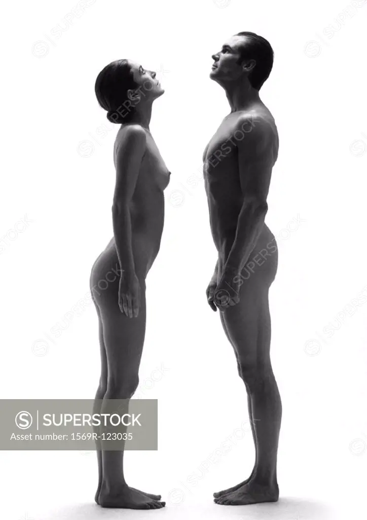 Nude man and woman standing face to face, looking up, side view, b&w