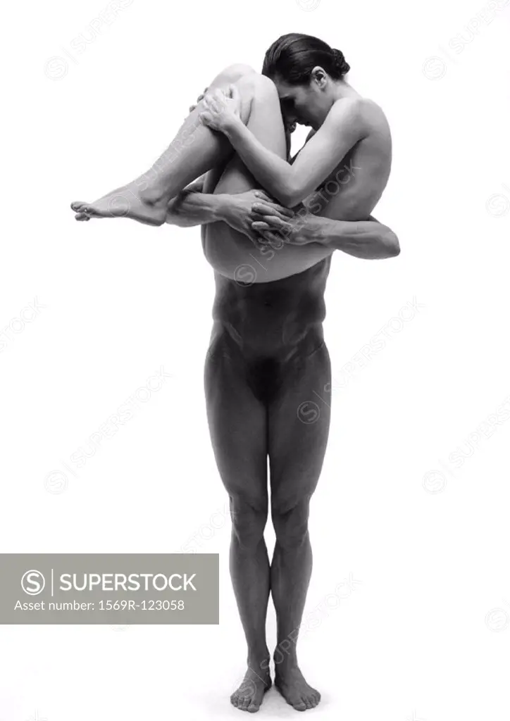 Nude man holding curled up nude woman in arms, b&w