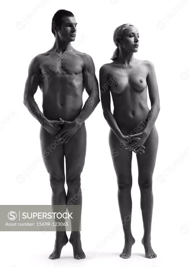 Nude man and woman standing on toes with hands covering groins, b&w