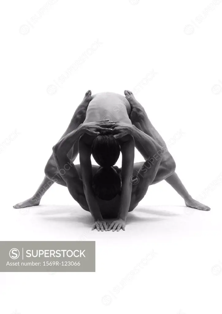 Nude man and woman, man on back with legs around woman bending over him, b&w