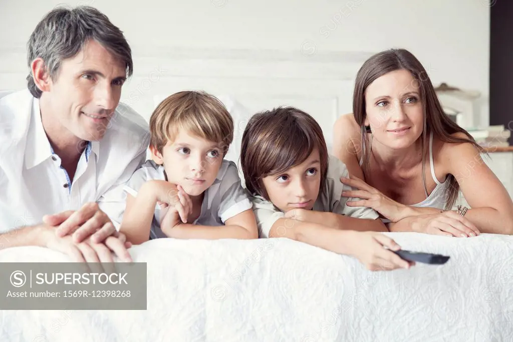 Family watching TV on bed, portrait