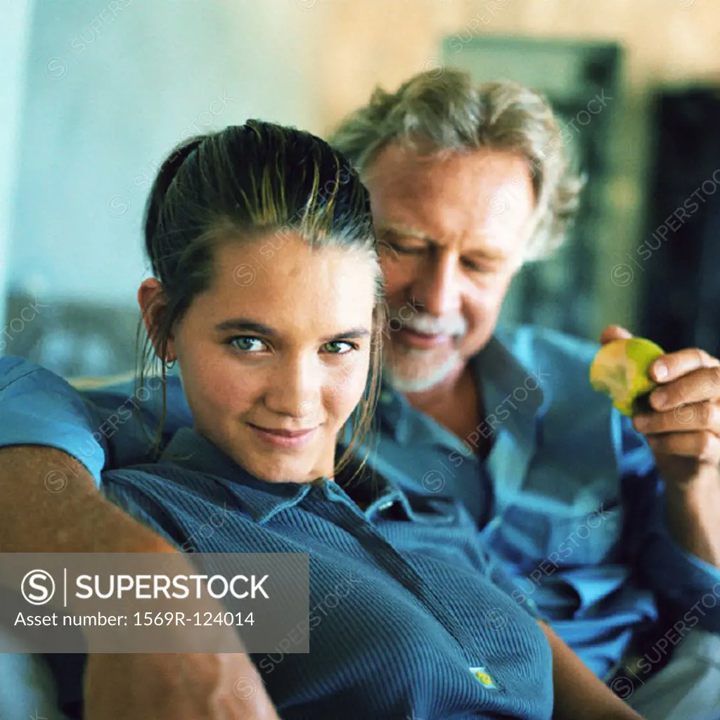 Teenage girl sitting with mature man, portrait