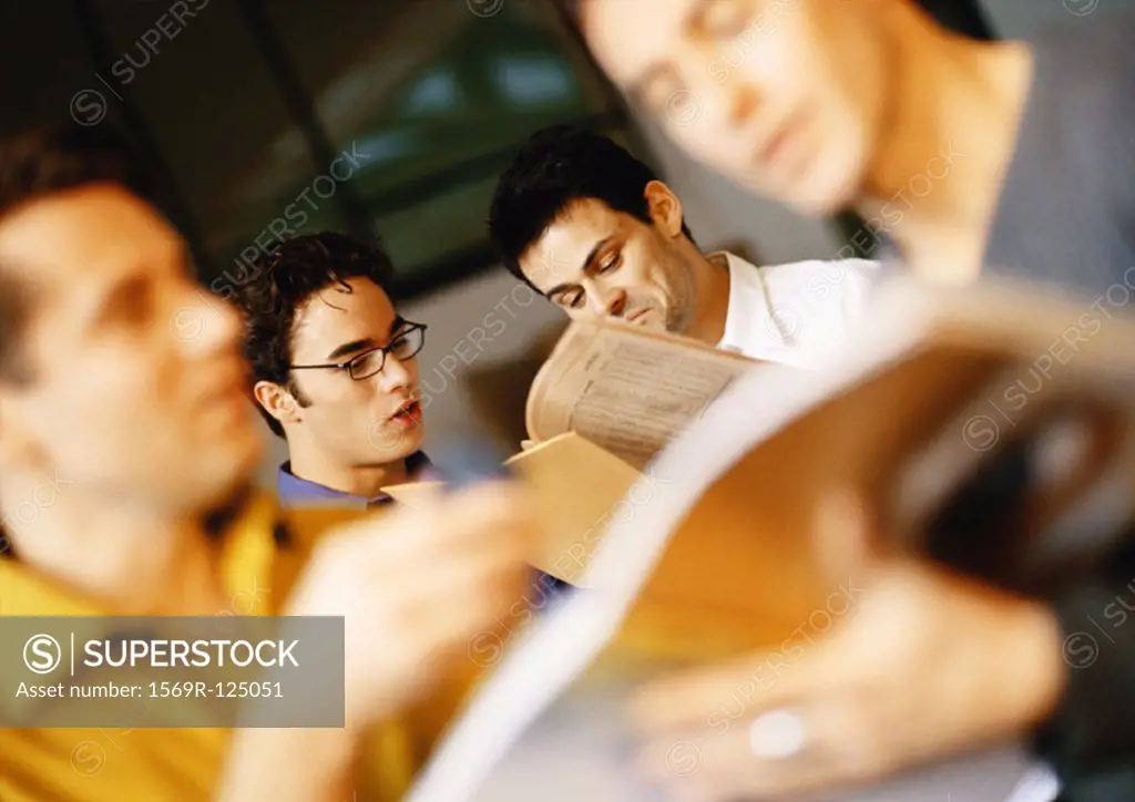 Men in office, looking at documents, blurred