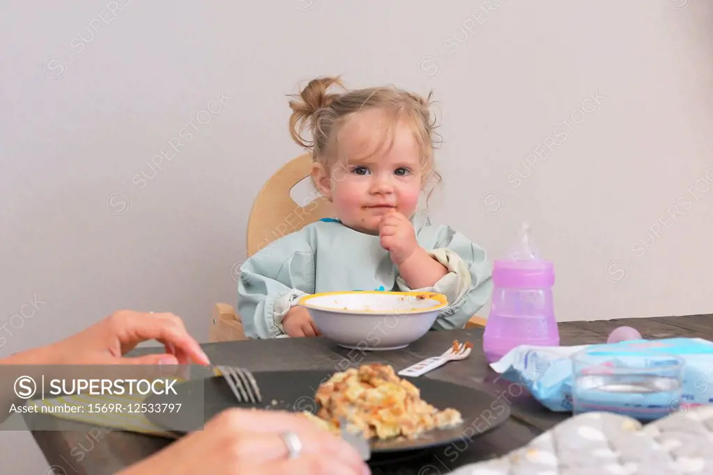 Baby sitting in high chair at table having meal