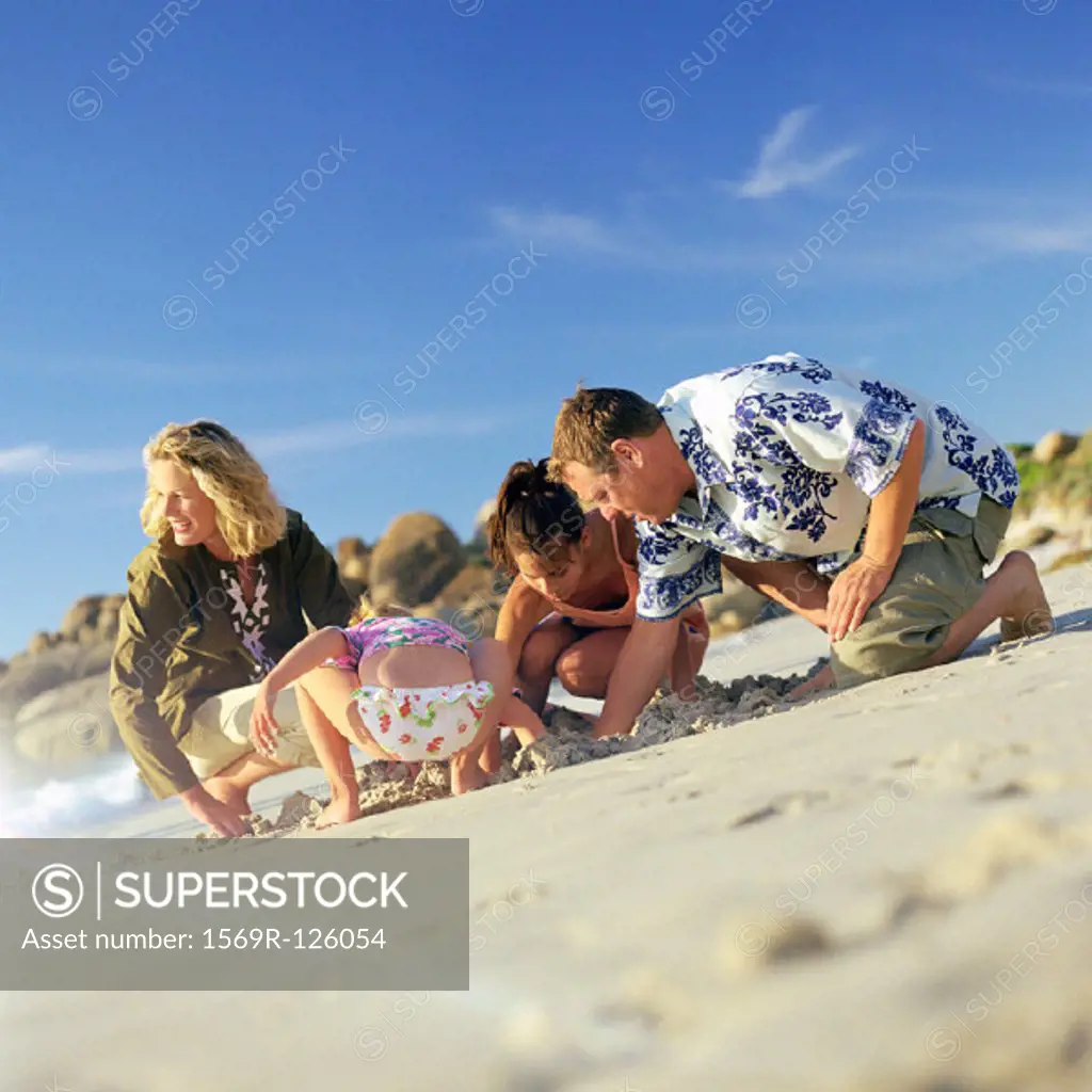 Couple and children digging in sand