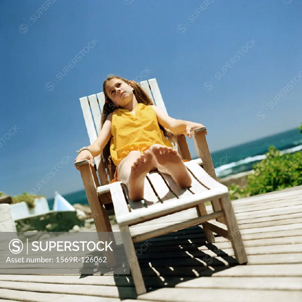 Girl sitting in deckchair, sea in background