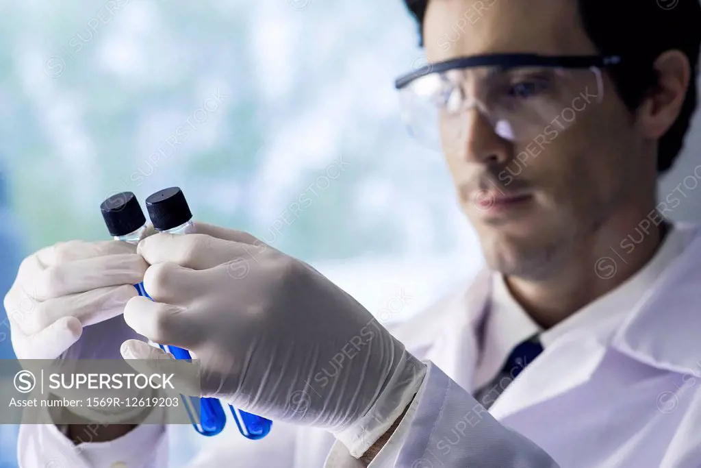 Scientist scrutinizing test tubes containing blue liquid in lab