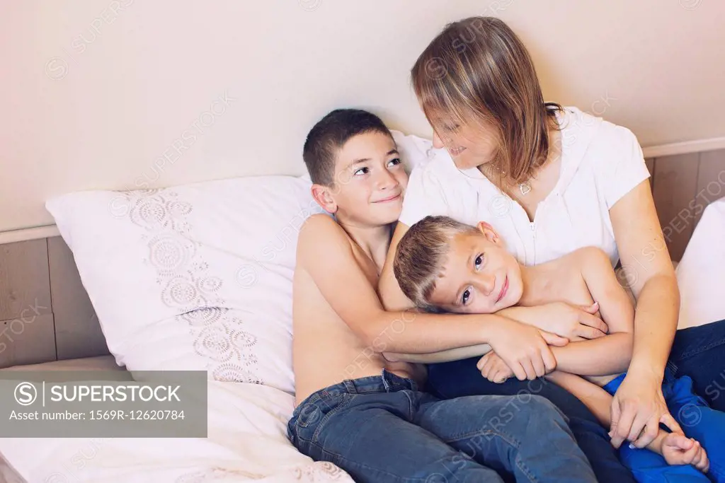 Mother and young sons relaxing together on bed