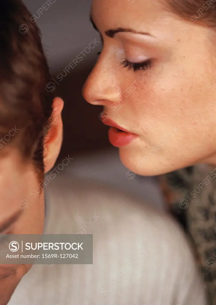Woman whispering into man´s ear, close-up